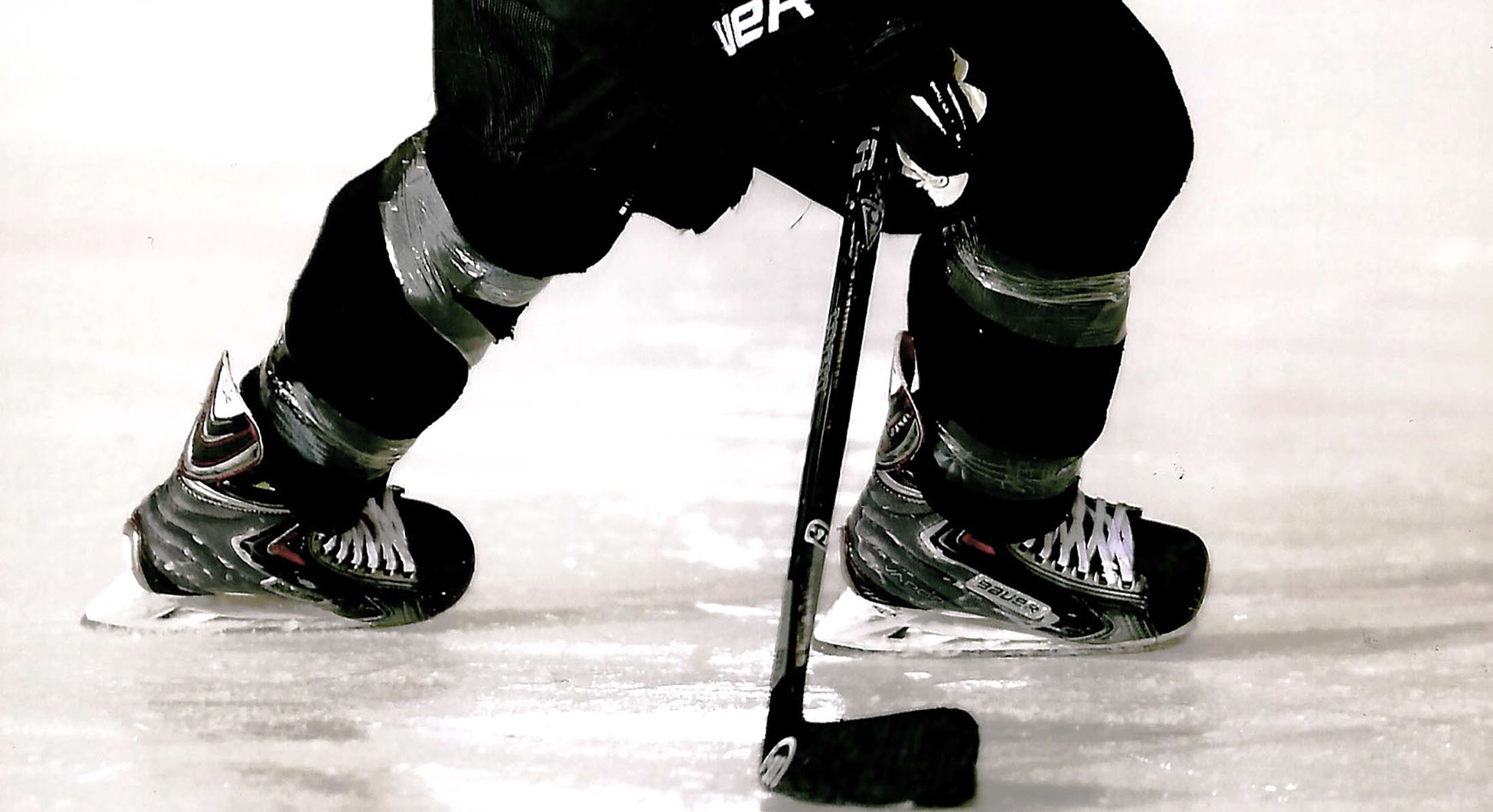 Eishockeyspieler mit Schläger und Schlittschuhen auf dem Eis